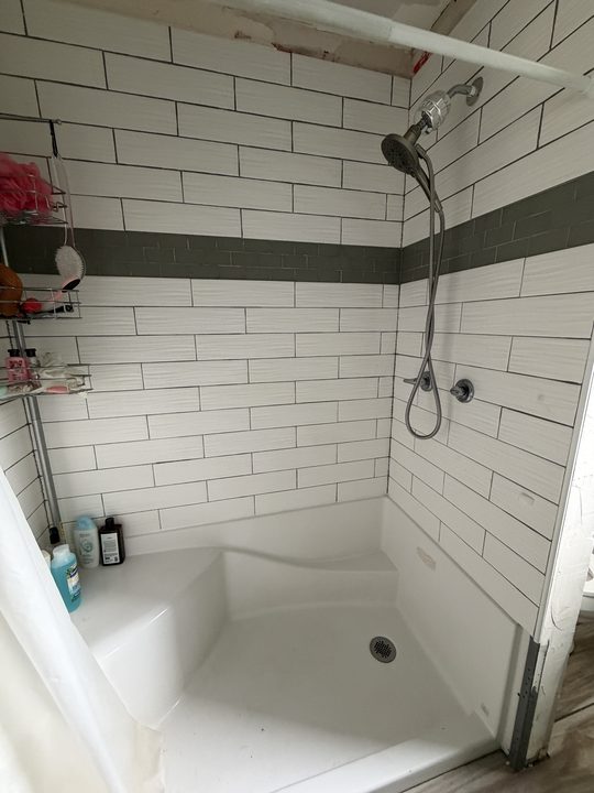 Before: white subway tile shower with two chrome grab bars