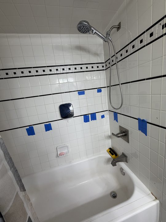 Before: tiled tub and shower with a grab bar on the back wall and one on the side wall