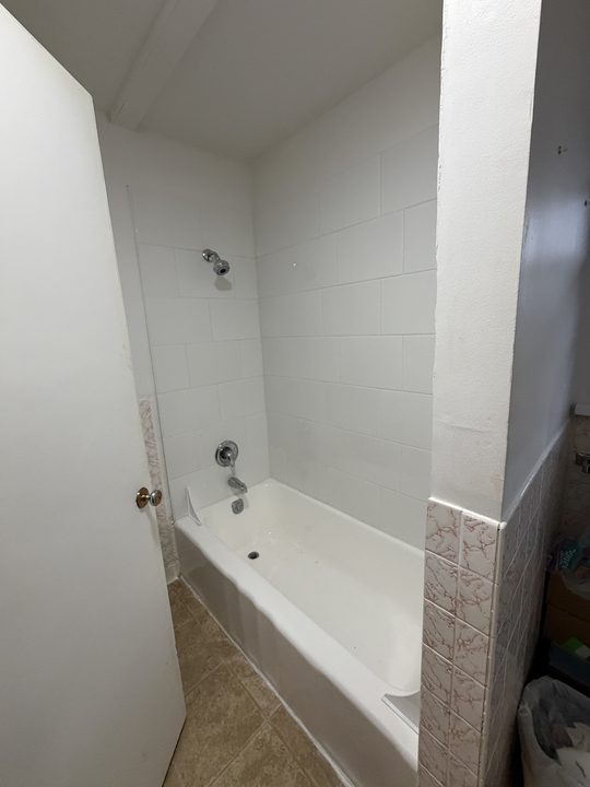 Before: tiled bathtub with three chrome grab bars
