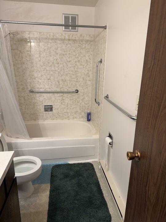 After: bathtub with grab bars on the tile and on the wall beside it