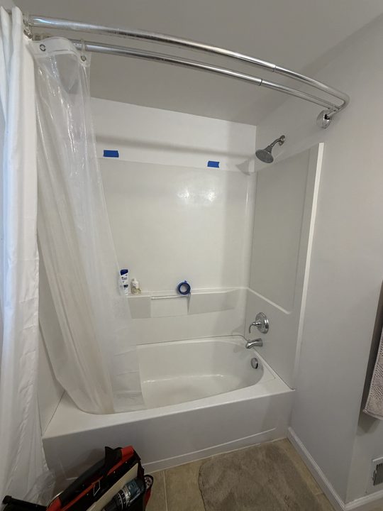 Before: white tub surround with a horizontal and a vertical grab bar