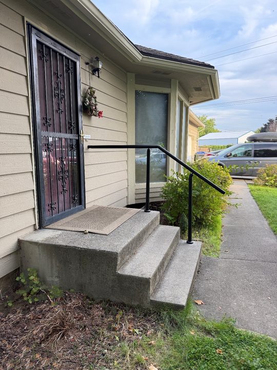 After: black handrail on three concrete front steps, running level across the landing beside the front door