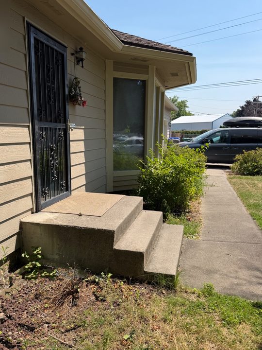 Before: black handrail on three concrete front steps, running level across the landing beside the front door