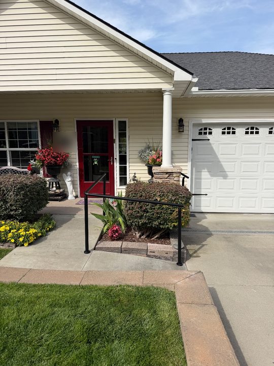 After: black handrail along a front walkway, wrapping the corner of a planter bed